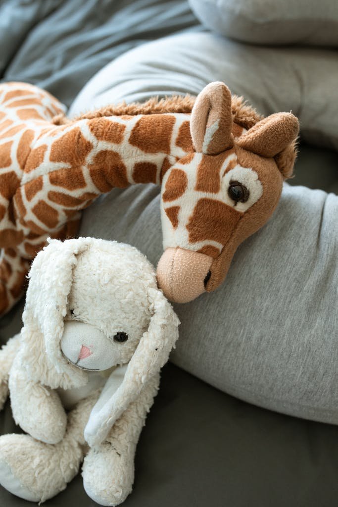 Soft giraffe and bunny toys on a cozy blanket, perfect for childhood comfort.