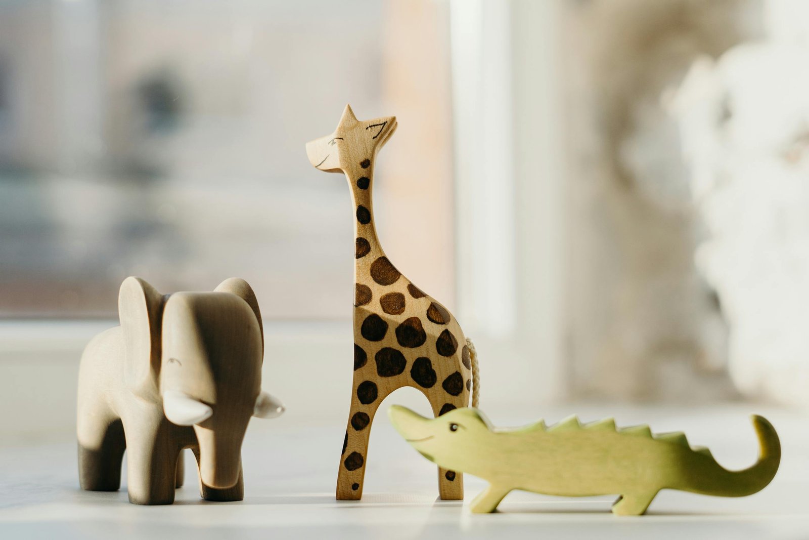 Wooden giraffe, elephant, and crocodile figures create playful decor. Ideal for kids' rooms.